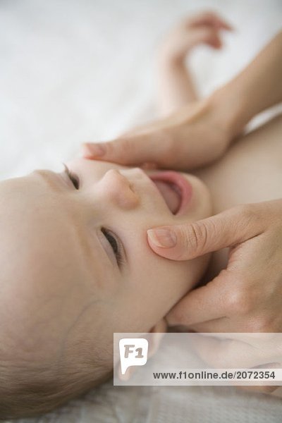 Die Hände einer Mutter im Gesicht eines Babys
