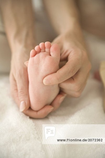 Eine Mutter massiert den Fuß eines Babys