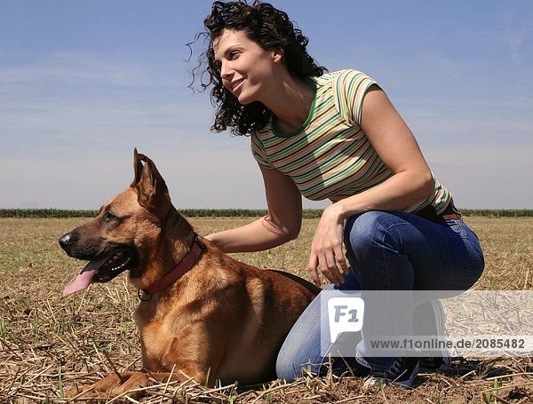 Young woman sitting with dog in field