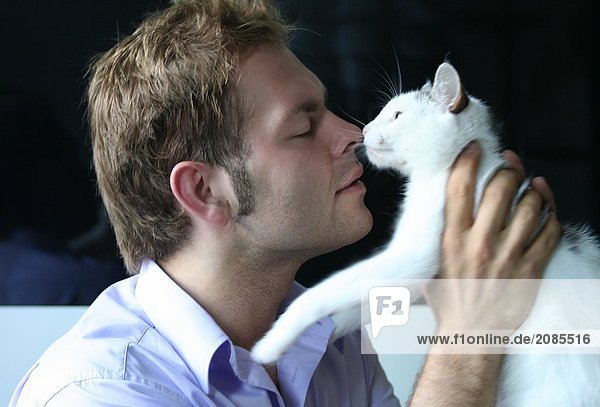 Close-up of young man playing with cat
