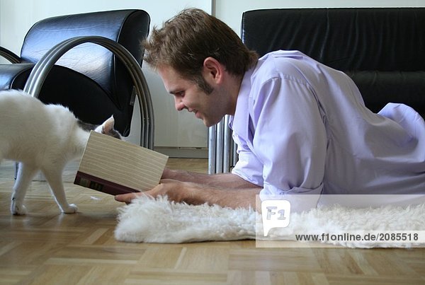 Side profile of young man playing with cat on floor