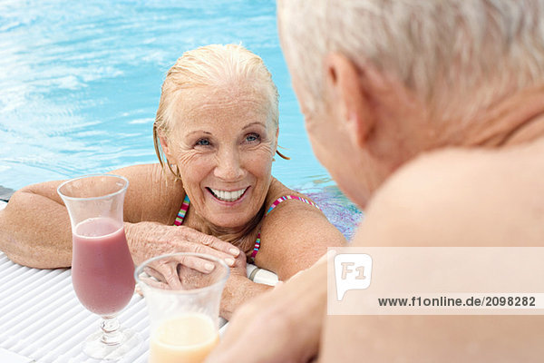 Deutschland  Seniorenpaar trinkt Cocktail am Pool