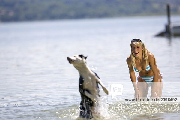 Young woman playing with dog in lake