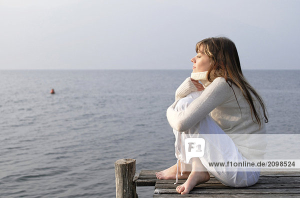 Italien  Gardasee  Junge Frau (20-25) am Steg sitzend