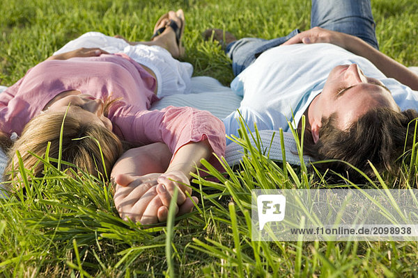 Couple lying in meadow  hand in hand