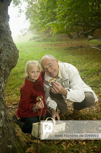 Germany Baden-Württemberg Swabian mountains Grandfather and granddaughter searching mushrooms in the forest portrait