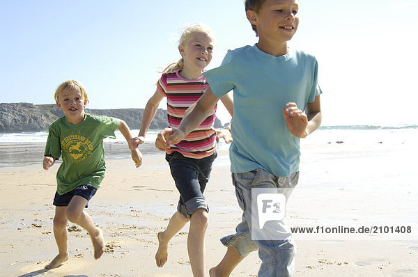 Two boys and girl running on beach
