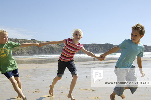 Zwei jungen und Mädchen spielen am Strand