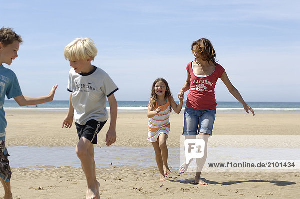 Frau mit ihren drei Kindern am Strand