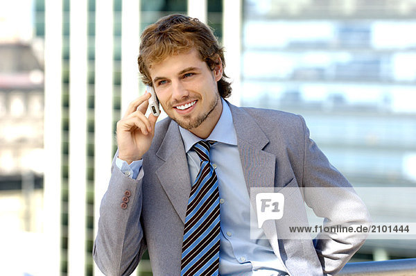 Businessman using mobile phone  smiling