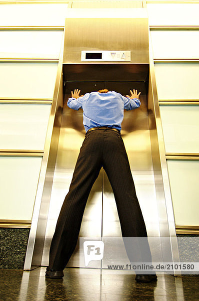 Geschäftsmann vor geschlossener Aufzugstür stehend  Blickwinkel niedrig