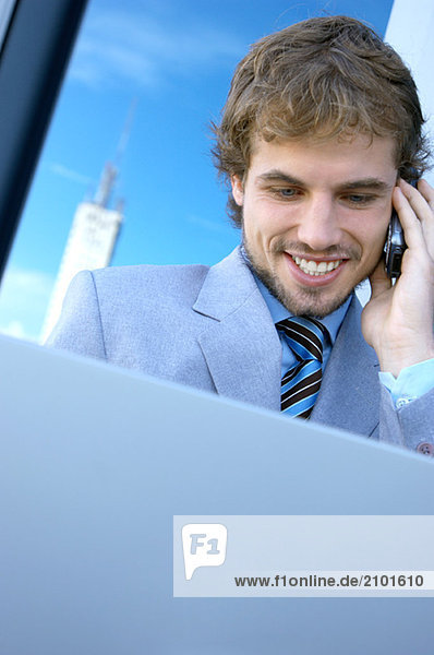 Young businessman using mobile phone and laptop  close-up