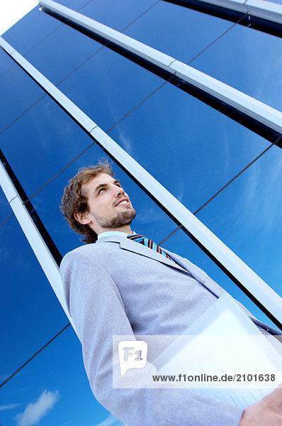 Young businessman holding file by office building  low angle view