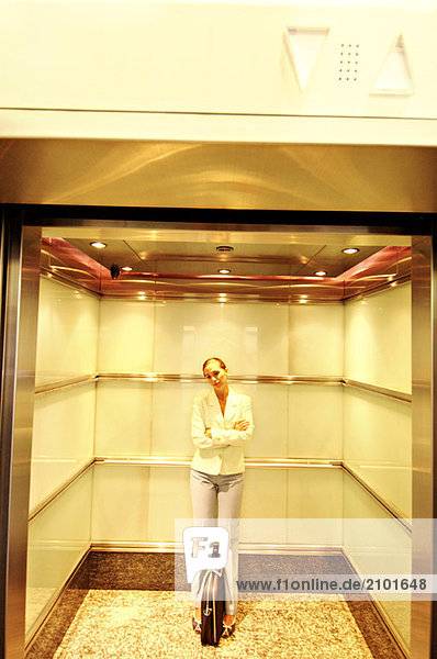 Businesswoman standing in elevator with folded arms