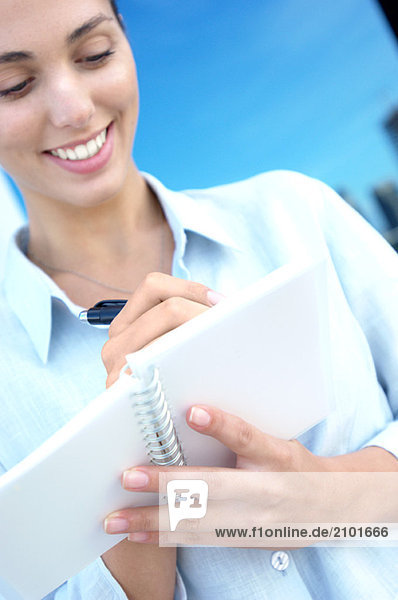 Businesswoman writing on notebook  smiling