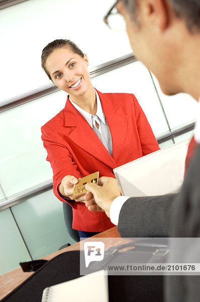 Geschäftsmann übergibt Kreditkarte an Geschäftsfrau im Büro