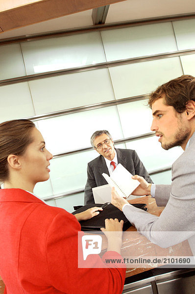 Businessmen and businesswoman conversing in office