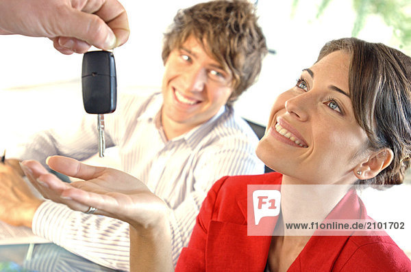 Autohändler übergibt Autoschlüssel an Kunden  lächelnd