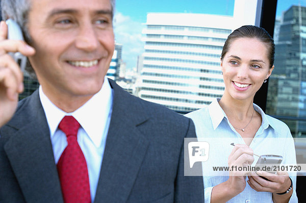 Business people using mobile phone  smiling