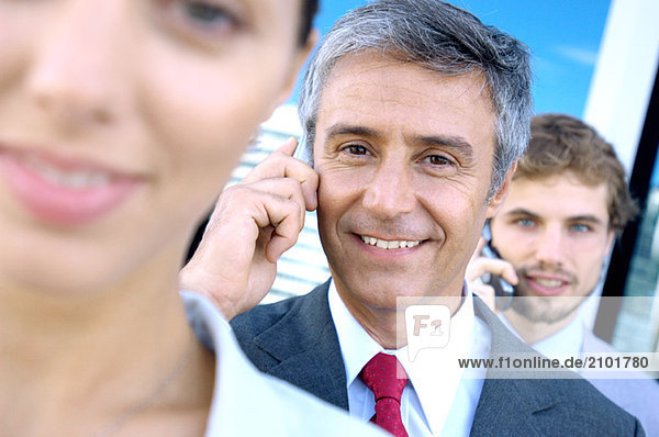 Geschäftsleute  die Mobiltelefone benutzen  lächelnd