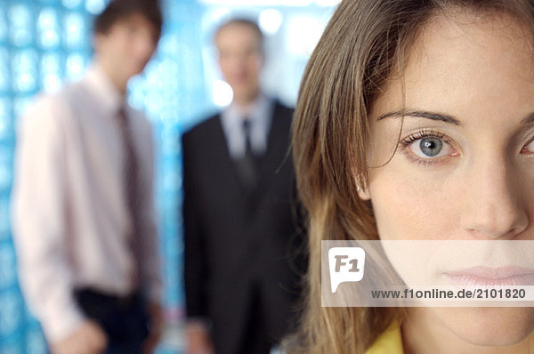 Businesswoman staring with colleagues in background