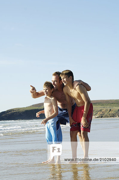 Man standing with his two sons on beach