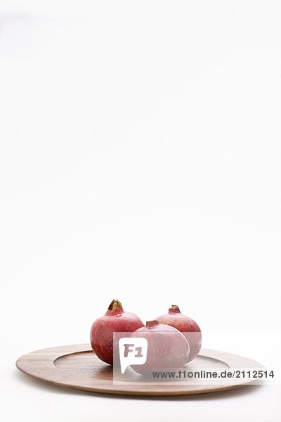 3 pomegranates on wooden plate