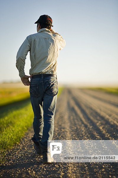 Man walking along gravelled road in rural Saskatchewan  Canada