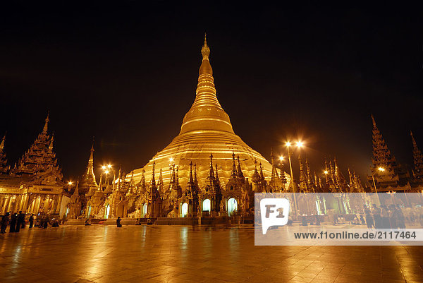 Group of people at Buddhist temple lit up during dusk  Shwedagon Pagoda  Yangon  Myanmar