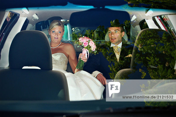 Brautpaar auf dem Rücksitz eines Autos