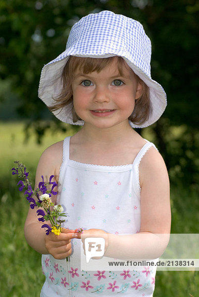 Kleines Mädchen mit Blumen auf einer Wiese
