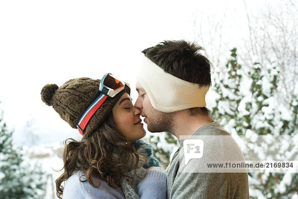 Junges Paar in Winterkleidung  Küssen  Seitenansicht