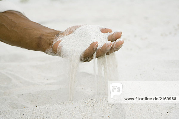 Mann hält eine Handvoll Sand  abgeschnittene Ansicht der Hand