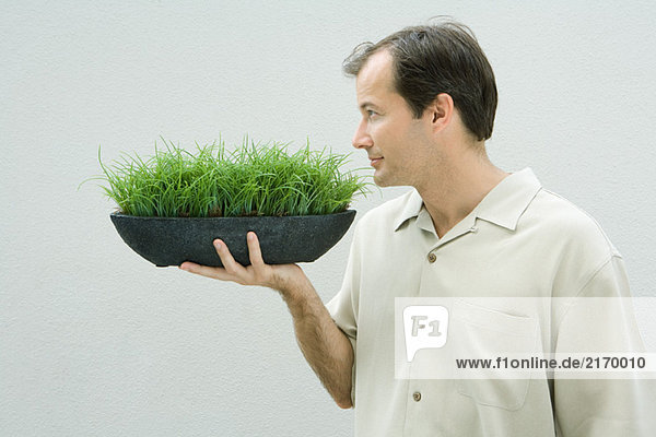 Man smelling bowl of grass  side view