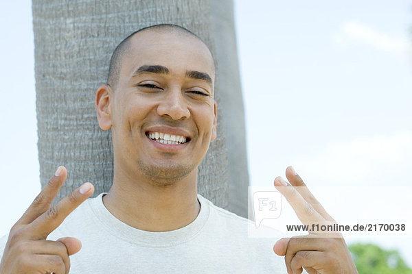 Man giving peace sign and smiling at camera  portrait