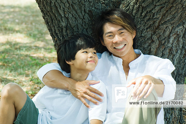 Vater und Sohn zusammen unterm Baum  Mann lächelt vor der Kamera