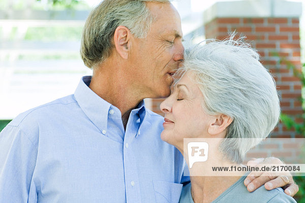 Mature man kissing wife's forehead  side view