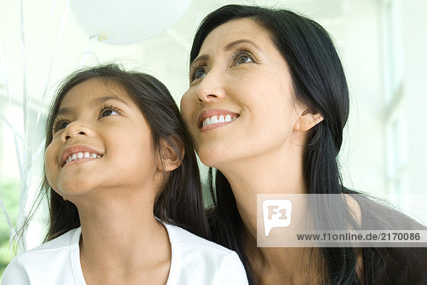 Mutter und Tochter schauen auf und lächeln zusammen  Nahaufnahme