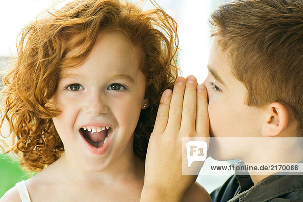 Boy whispering in girl's ear  close-up