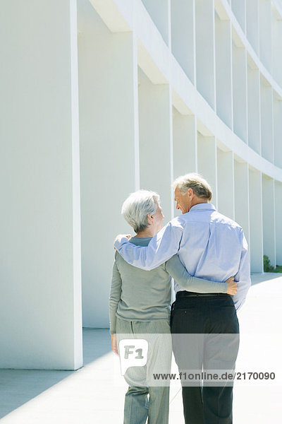 Mature couple walking with arms around each other  rear view