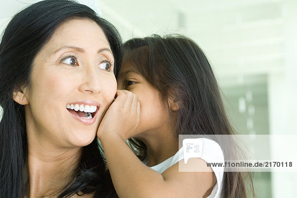 Mädchen flüstert Mutter ins Ohr  Nahaufnahme