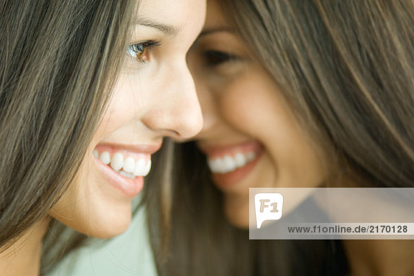 Zwei Zwillingsschwestern lächeln  von Angesicht zu Angesicht  Profil