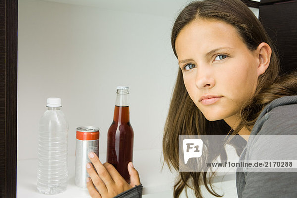 Teen girl next to variety of drinks  reaching for bottled soft drink