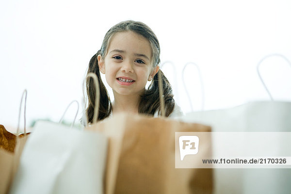 Kleines Mädchen lächelt  Einkaufstaschen im Vordergrund