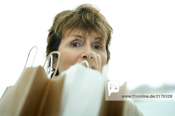Frau schaut über Einkaufstaschen