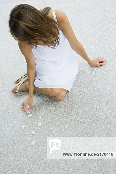 Woman sitting on the ground arranging pebbles