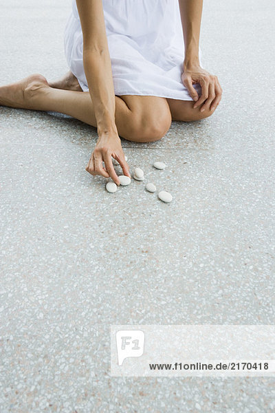 Woman kneeling on the ground arranging pebbles  cropped view