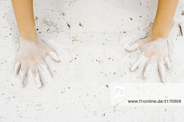 Kind macht Handabdrücke in Sand  abgeschnittene Ansicht der Hände