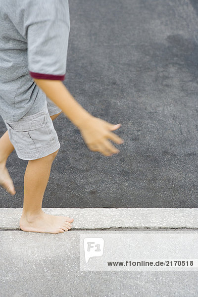 Kind geht auf dem Bürgersteig an einem Riss entlang  Blick in den Ausschnitt