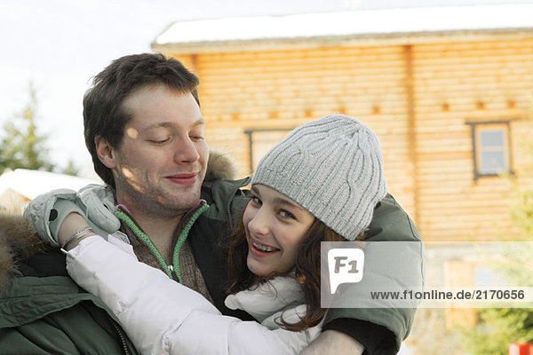 Teen girl hugging young man  looking over shoulder at camera  laughing